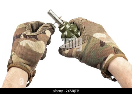 Man`s hand in tactical gloves removes safety pin of old green shrapnel Hand Grenade Weapon of War Isolated on White background Stock Photo